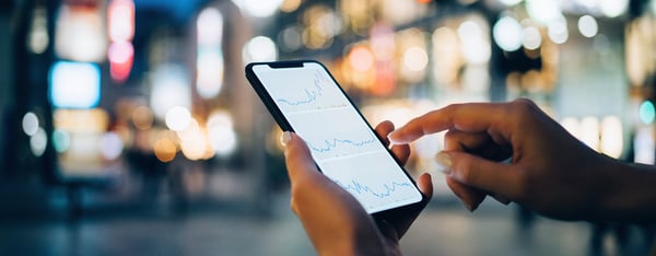 Hand with mobile phone showing a line graph