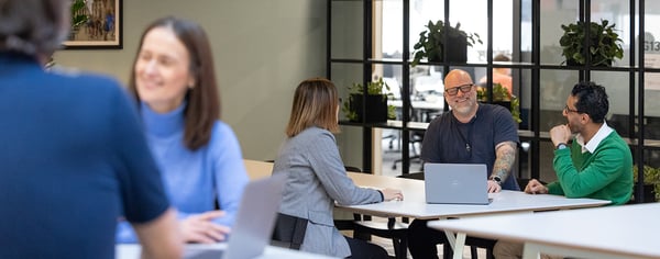Colleagues chatting looking at laptops