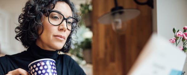 Woman reading newspaper and drinking coffee