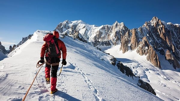 Mountaineer walking along snow capped ridge