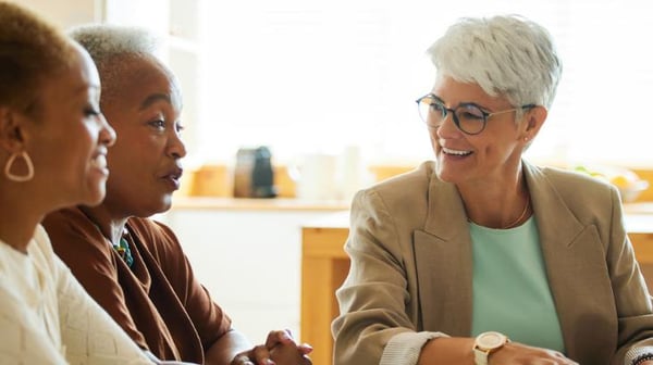 Three women talking while sat around a table