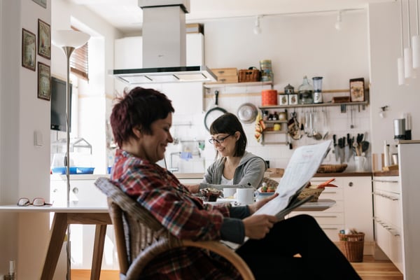 Two women laughing in kitchen over breakfast