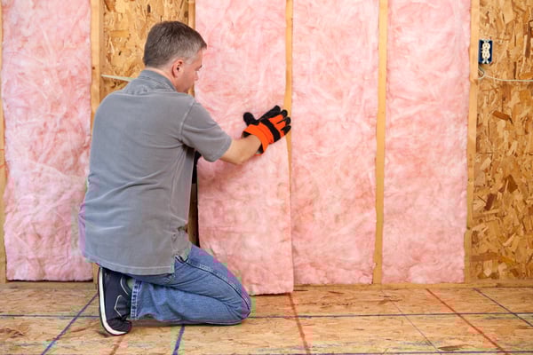 A tradesman adding insulation to a wall