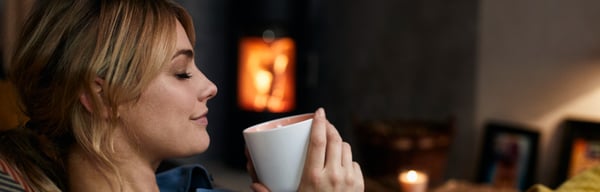 Lady keeping warm at home near the log fire