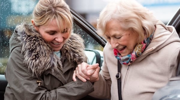 Young woman helping old lady out of car
