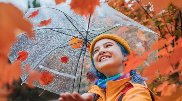 Woman smiling holding an umbrella in the rain