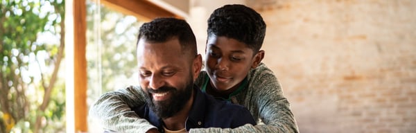 Father and teenage son smiling and hugging