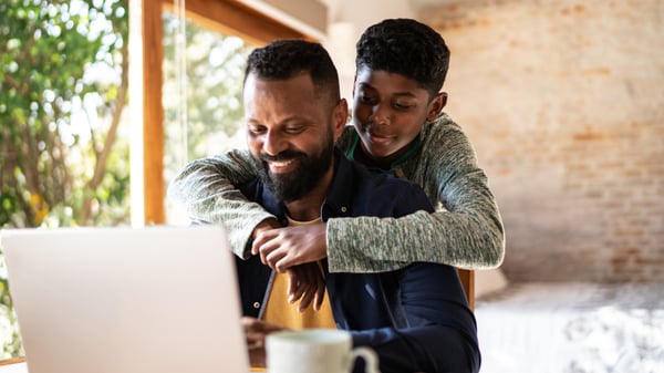 Father and teenage son smiling and hugging