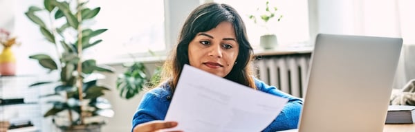 Woman looking at paperwork and laptop