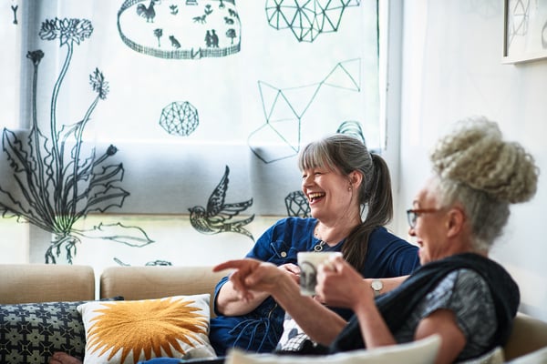 Two women laughing on the sofa together
