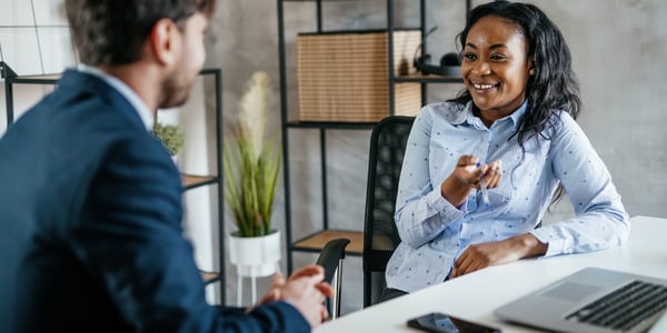 Colleagues talking at desk with laptop and mobile