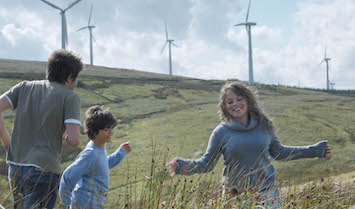 Happy young family in a field with windfarms
