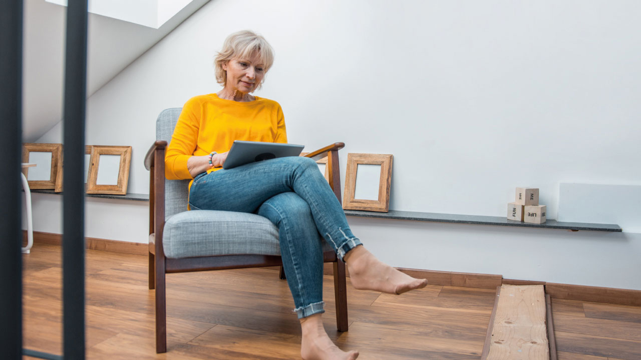 Woman in yellow top in armchair looking at laptop