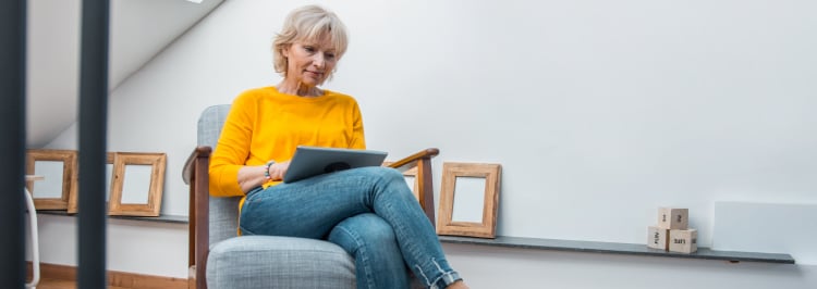 Woman in yellow top in armchair looking at laptop