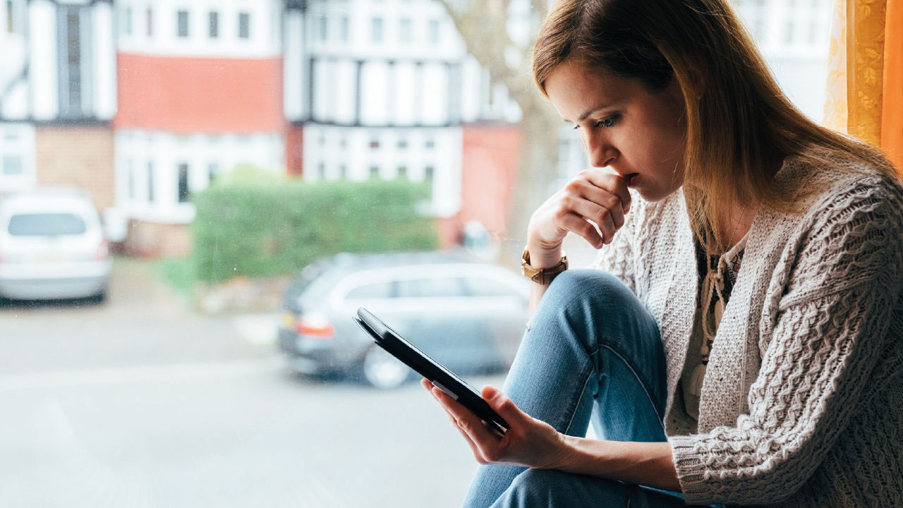 Woman in front of window looking at laptop