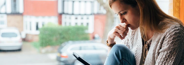 Woman in front of window looking at laptop