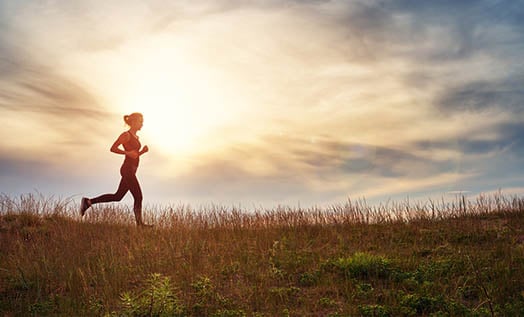 Woman jogging in the countryside at sunrise