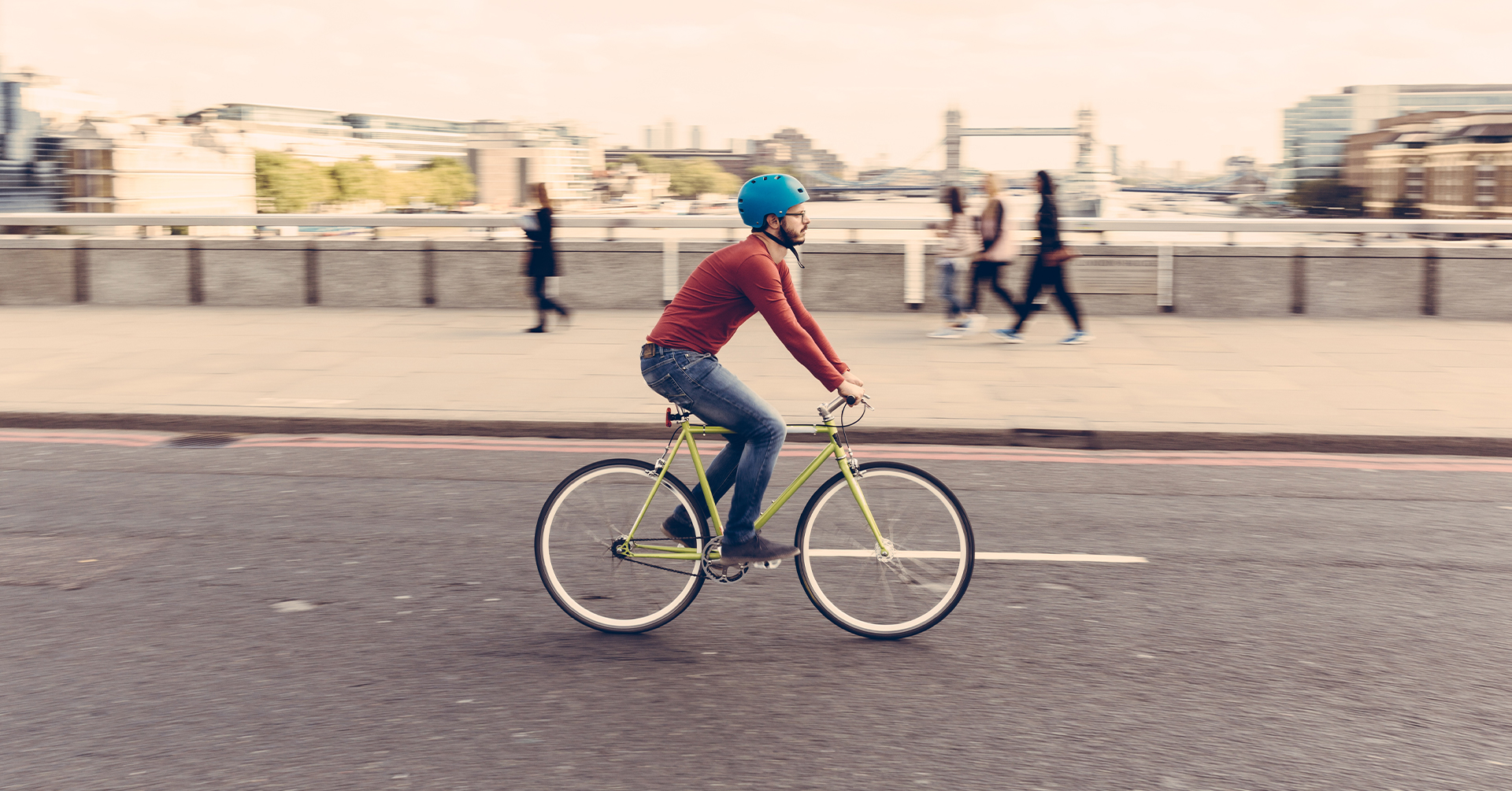Trendy man on bike cycling over a bridge in London