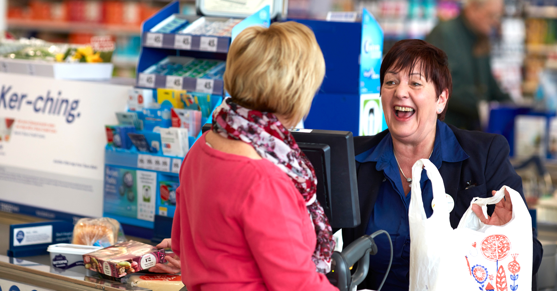 Colleague at the checkout chatting with customer and smiling