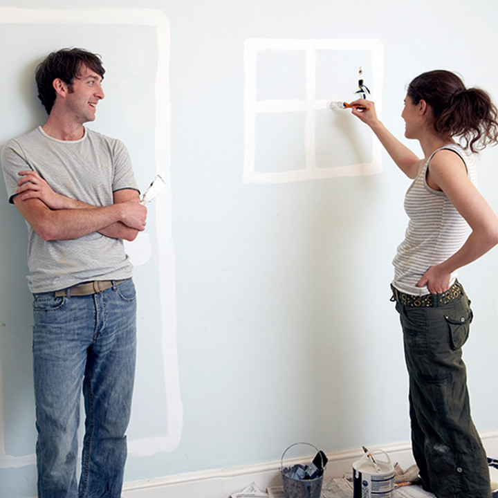 Couple painting doors and windows on wall