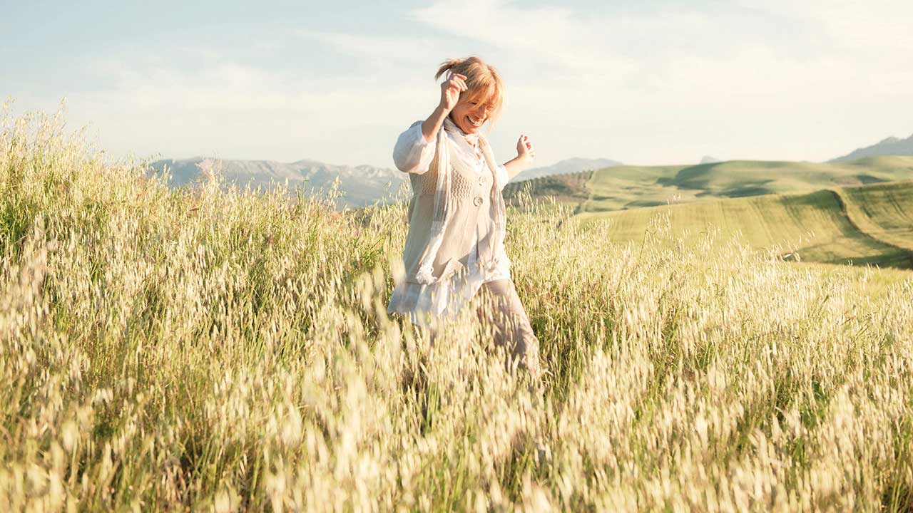 Woman running in a field of long grass