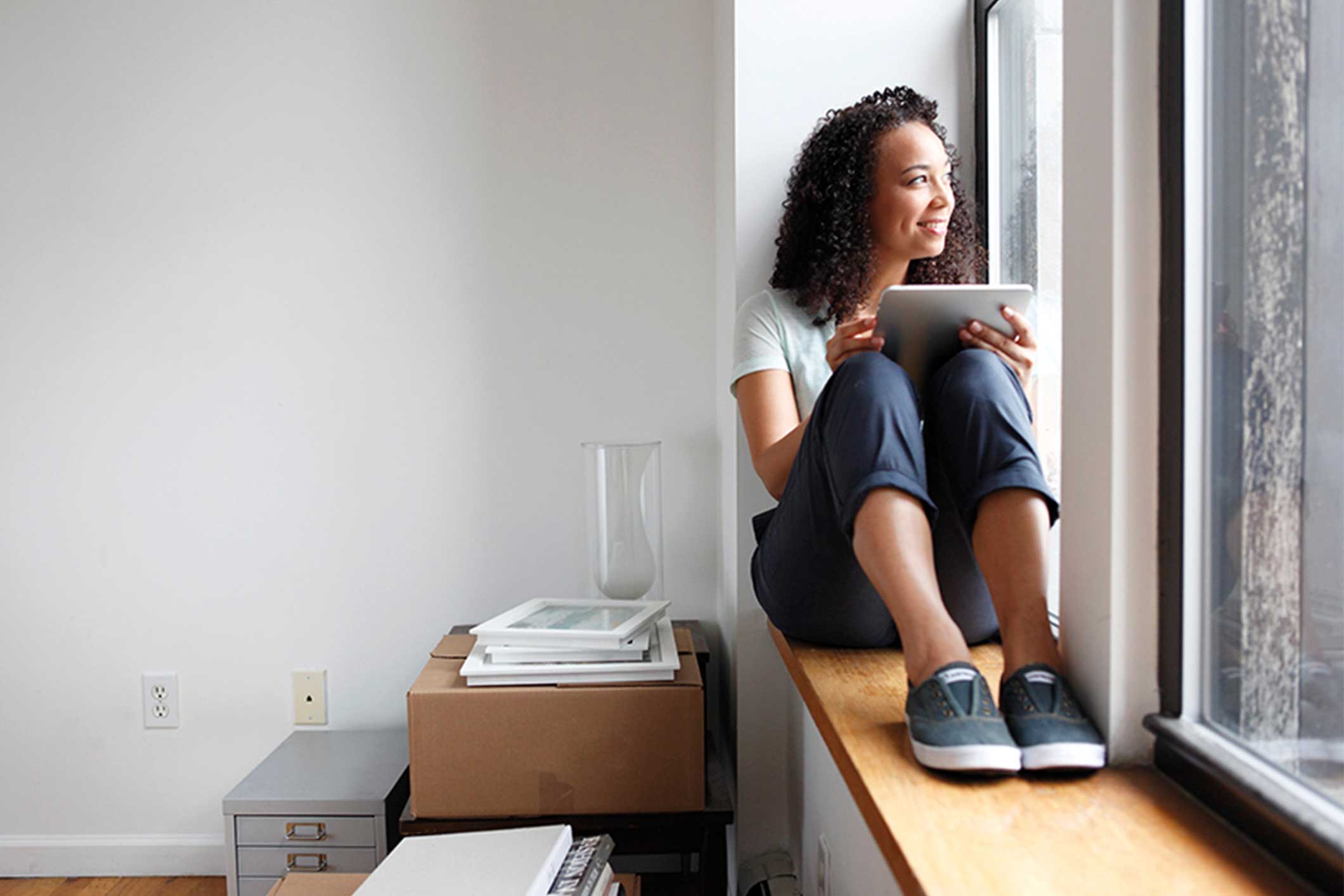 Young woman on tablet looking out of the window