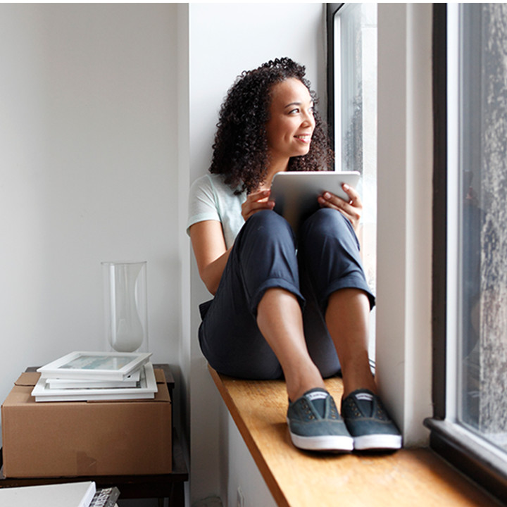 Young woman on tablet looking out of the window