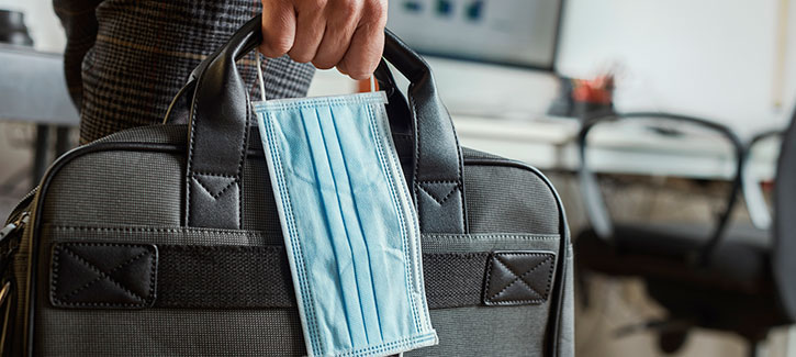 office worker carrying laptop bag and face mask