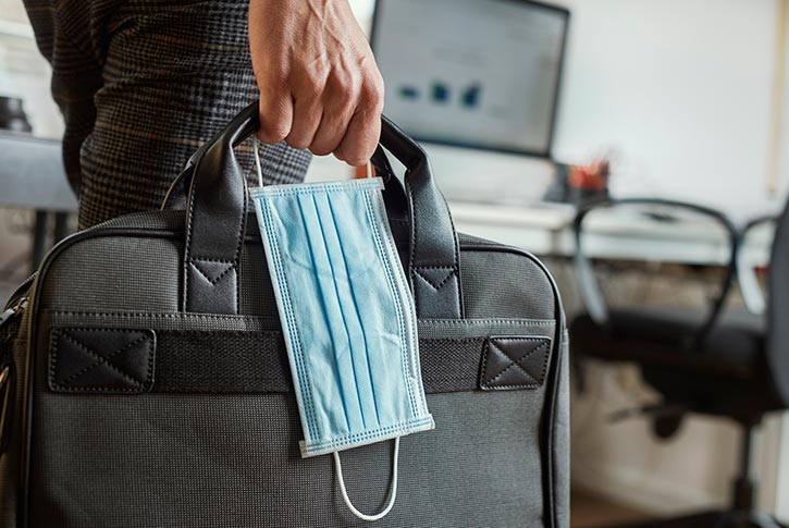 office worker carrying laptop bag and face mask
