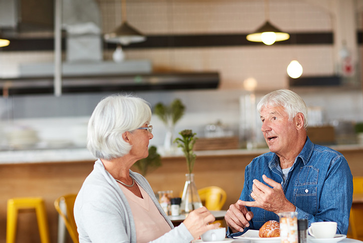 Older couple chatting over breakfast in cafe