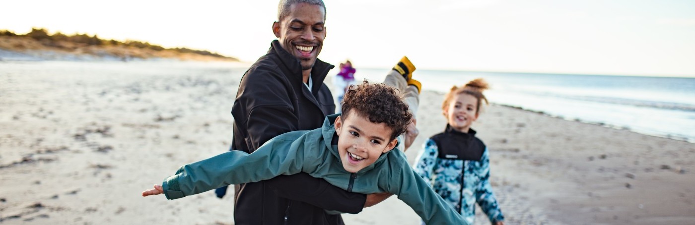 family-on-beach-father-lifting-son