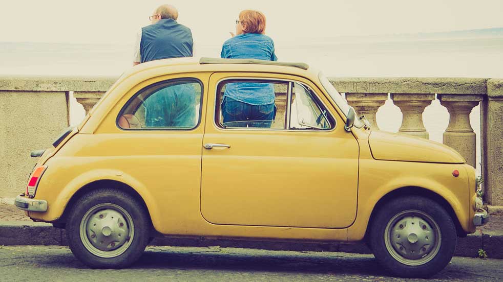 Two people standing by a car admiring the Naples view