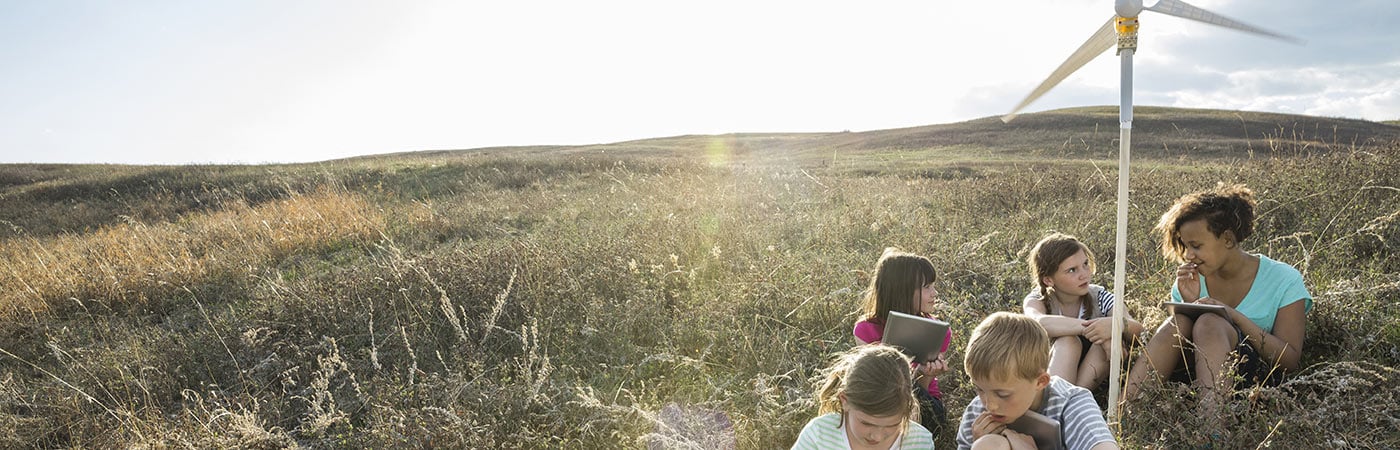 Group of children beside a mini wind turbine in the countryside