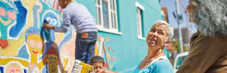 Community group painting bright mural on local building together