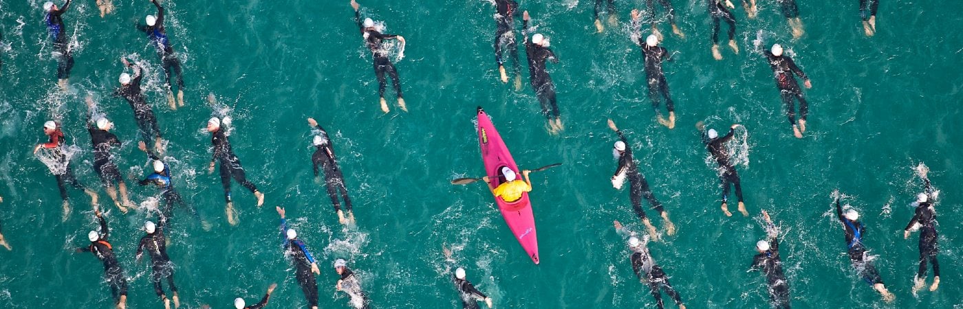 Canoeist surrounded by swimmers