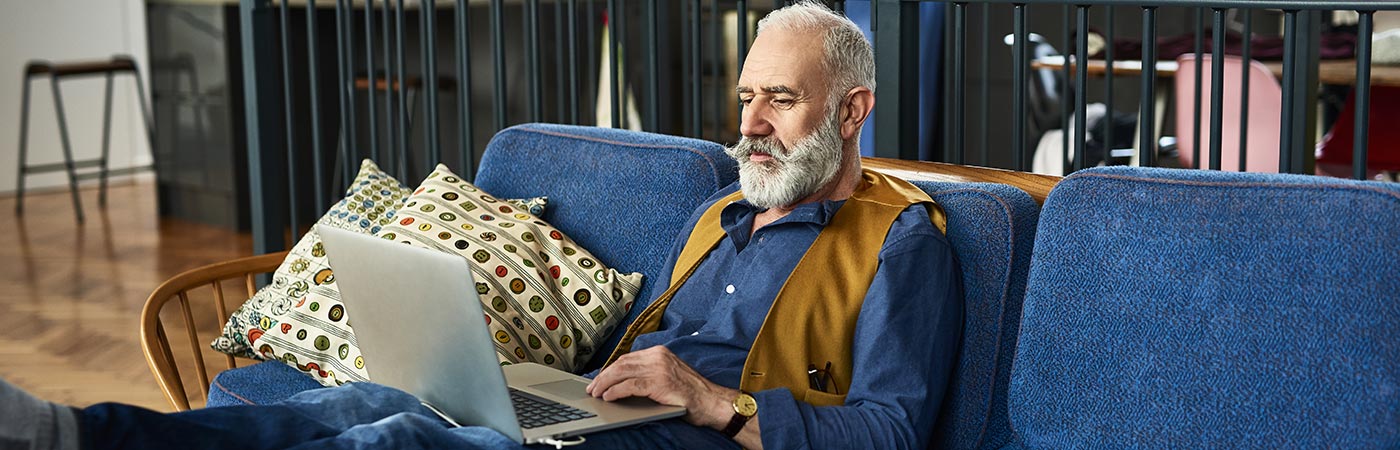 Senior man with trendy moustache looking at something on laptop