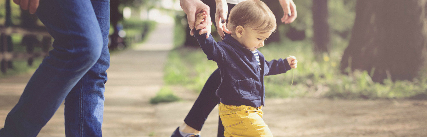 A toddler holding an adult's hand.