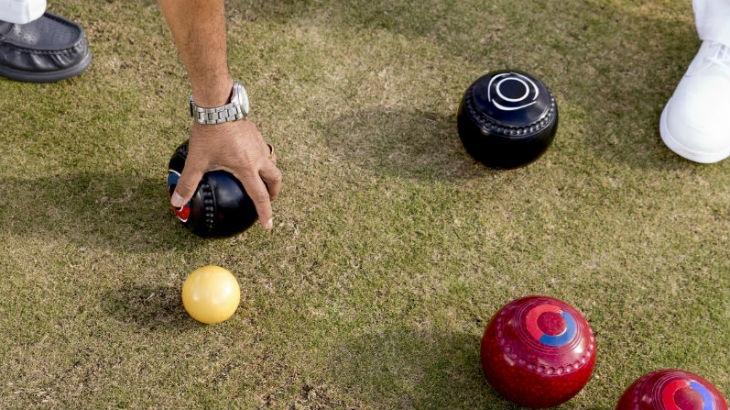Lawn bowls on a lawn with a hand adjusting them.