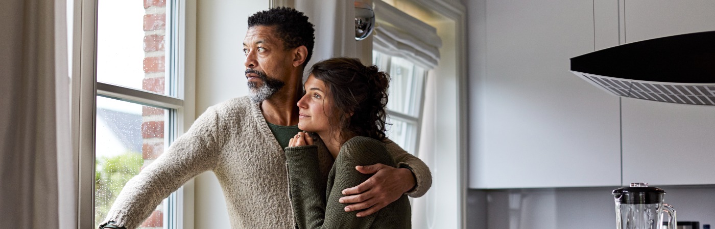 Couple standing at window looking somber