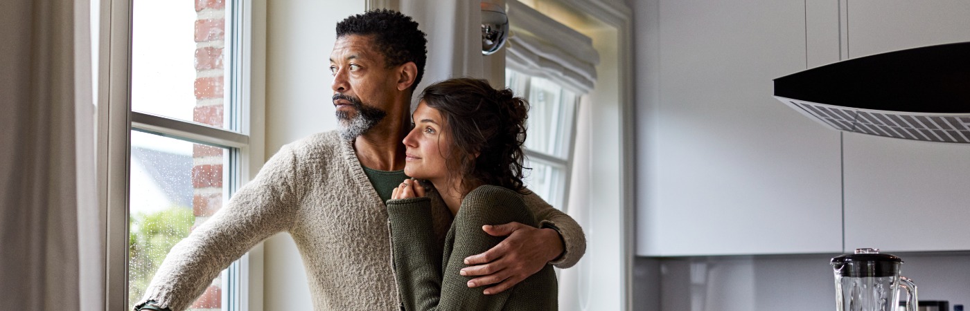 Couple standing at window looking somber