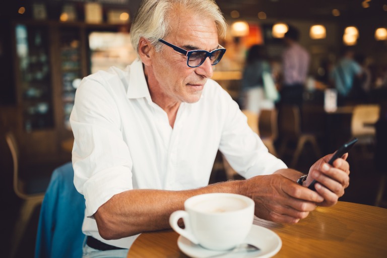 senior man in cafe using smart phone
