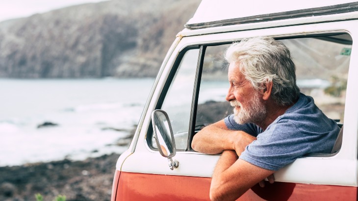Senior man in vintage camper on holiday