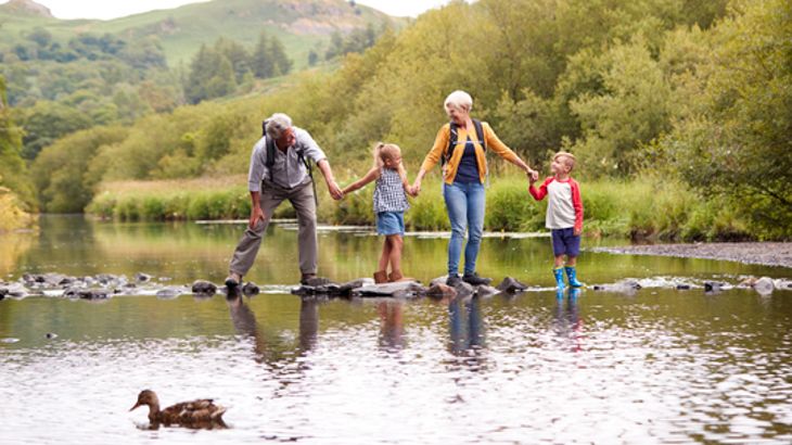 Grandparents with grandchildren on stepping stones on river
