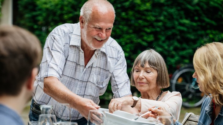 Senior man passing food at BBQ