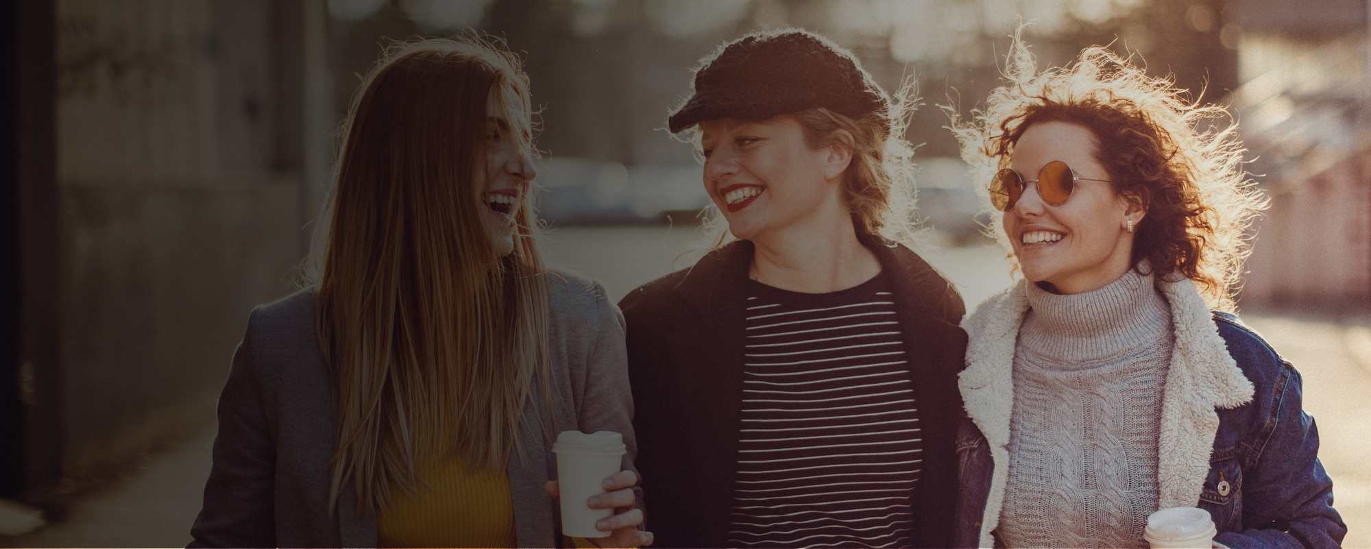Three ladies strolling and drinking coffee