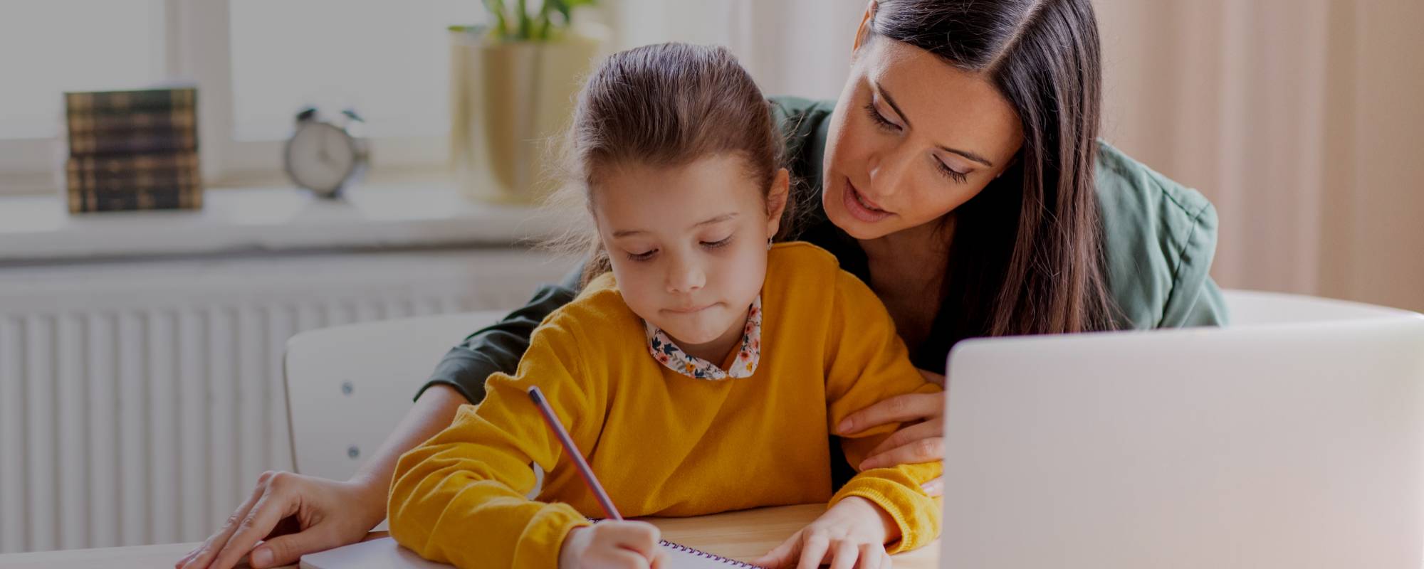 Mum teaching daughter at table
