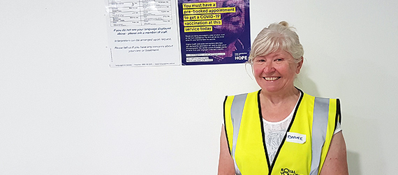 Diane standing in front of a COVID poster
