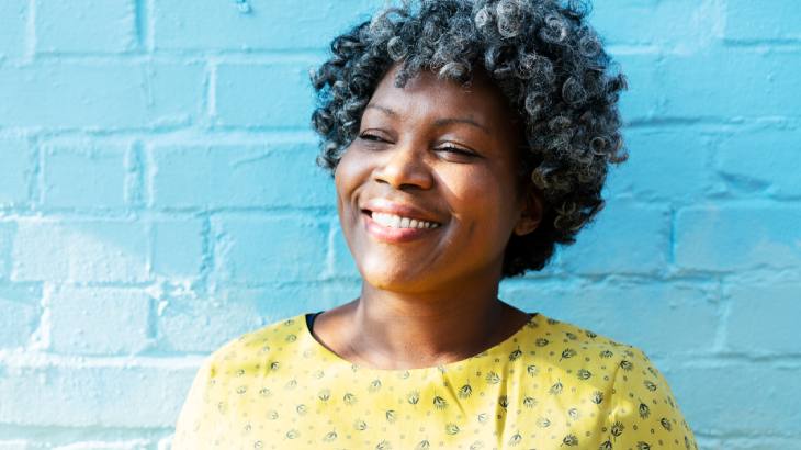 Woman against a blue wall, smiling
